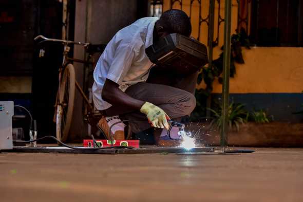Jeremiah Brian Nkuutu welds an ambulance carrier. The ambulances are constructed in Uganda with locally sourced materials and by locals. [Nicholas Bamulanzeki/Al Jazeera]